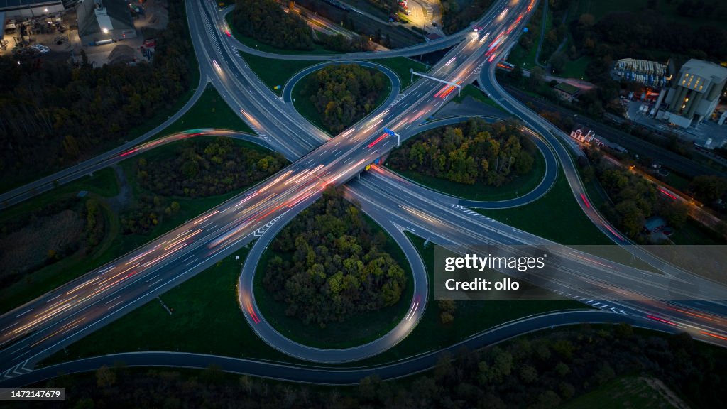 Intercâmbio rodoviário e distrito industrial ao anoitecer - vista aérea