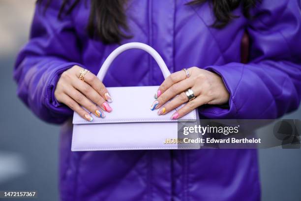 Samia Laaboudi wears a silver Love ring from Cartier, rings, a pale purple shiny leather handbag from Jacquemus, a neon purple shiny leather bomber...