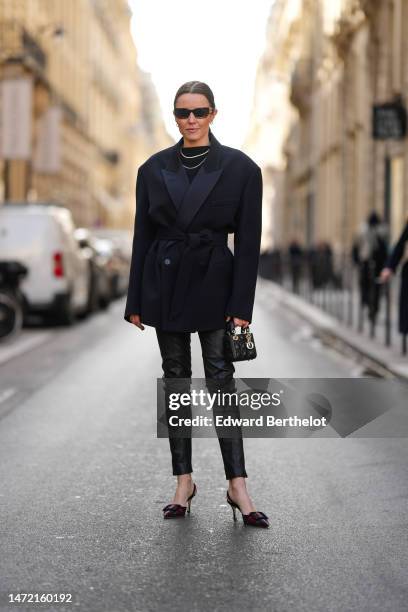 Chloe Street wears brown sunglasses from Miu Miu, silver small earrings, silver chain necklaces, a black wool pullover, a black belted coat, black...