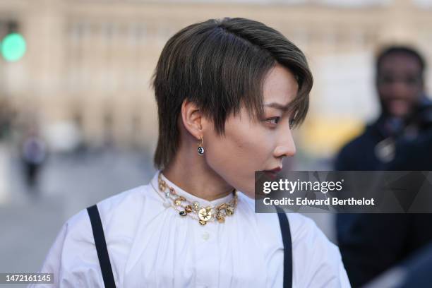 Liu Yuxin wears a gold large necklace from Dior, a white high neck / puffy long sleeves blouse, a black squared-neck / corset tank-top, outside Dior,...