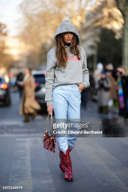 Guest wears a pale gray with red and pink embroidered pattern hoodie sweater, pale blue shiny leather skinny pants, a burgundy coins handbag from...