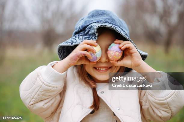 bunte ostereier in kleiner mädchenhand. kinder sammeln bemalte dekorationseier im frühlingspark. kinder jagen im freien nach eiern. - ostereier wiese stock-fotos und bilder