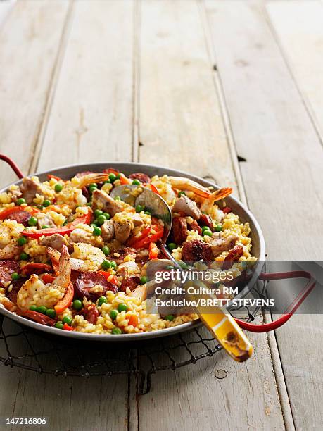 pan of paella on wooden table - paella stock-fotos und bilder