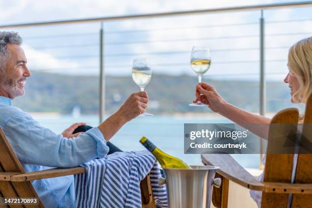 reifes paar trinkt wein auf dem deck. - man on the beach relaxing in deckchair stock-fotos und bilder