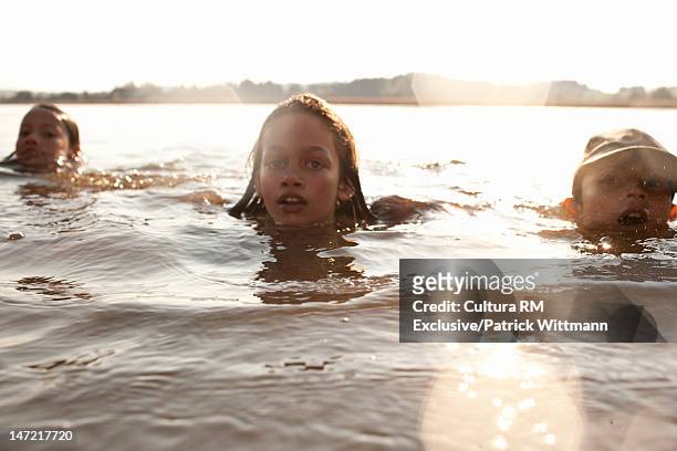 children swimming together in lake - lens flare nature stock pictures, royalty-free photos & images