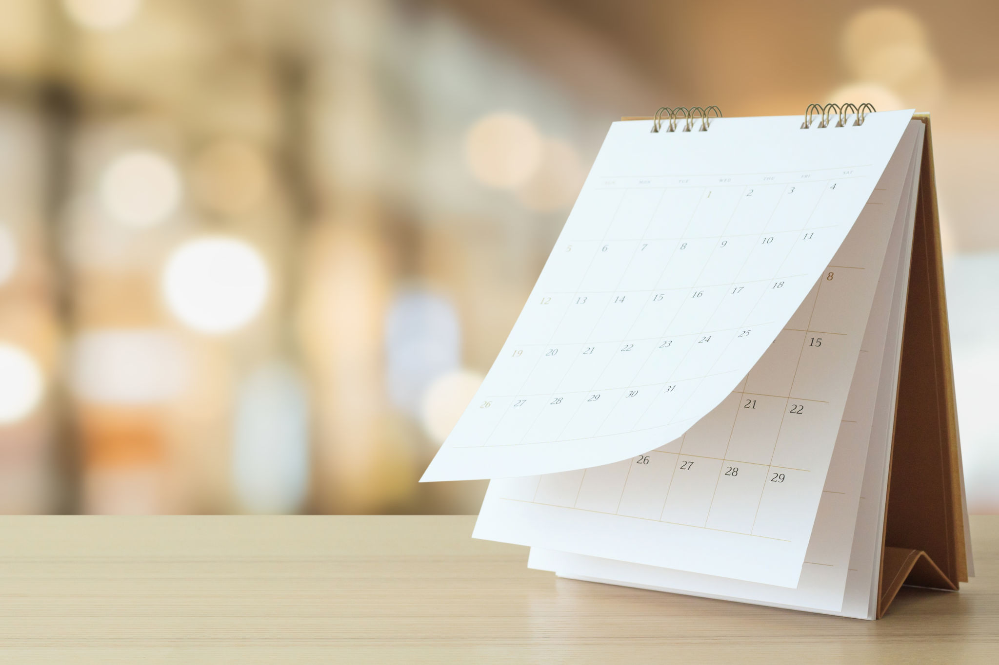 desk calendar on table with blurred bokeh background appointment and business meeting concept desk calendar on table with blurred bokeh background appointment and business meeting concept