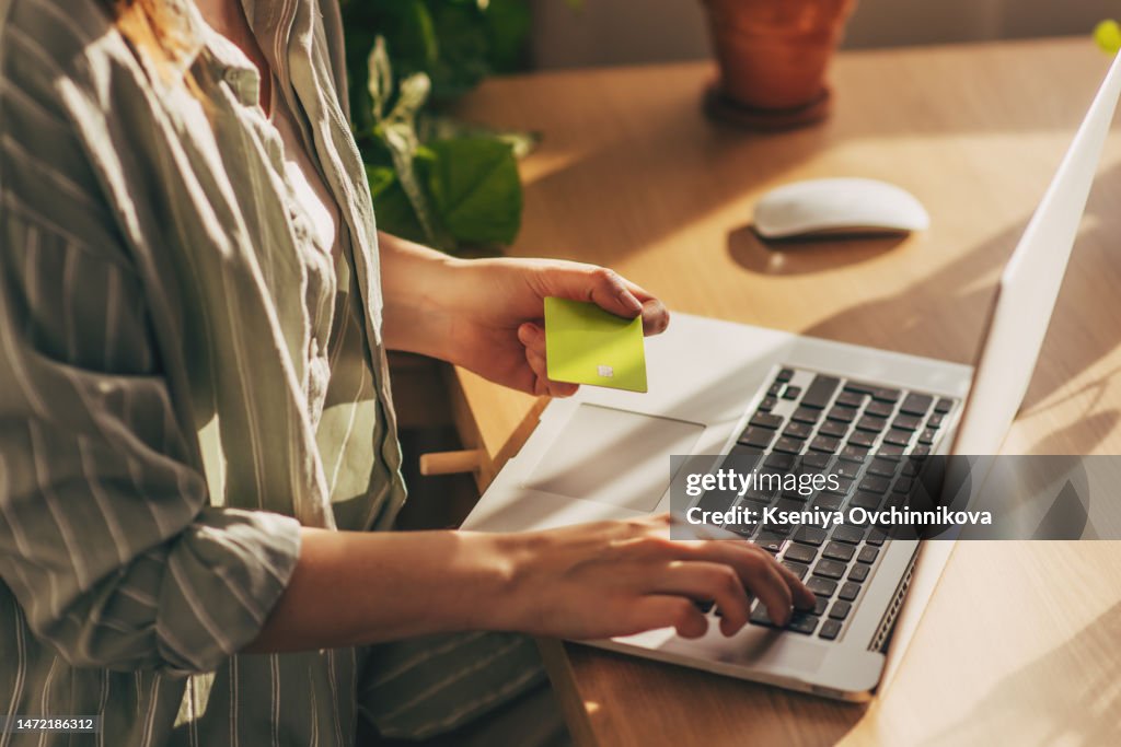 Hands holding plastic credit card and using laptop. Online shopping concept. Toned picture