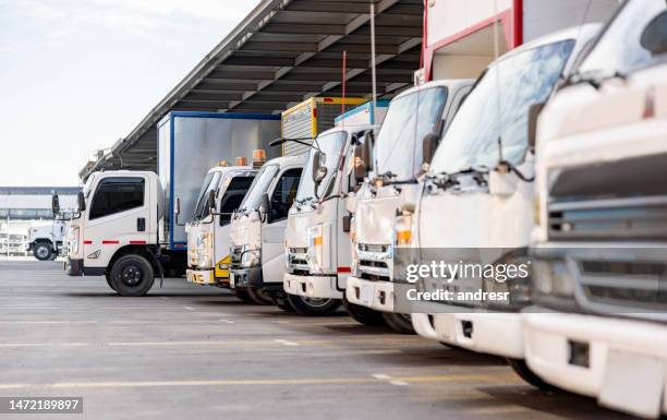 camiones estacionados en un almacén de distribución listos para entregar algo de carga - transito fotografías e imágenes de stock