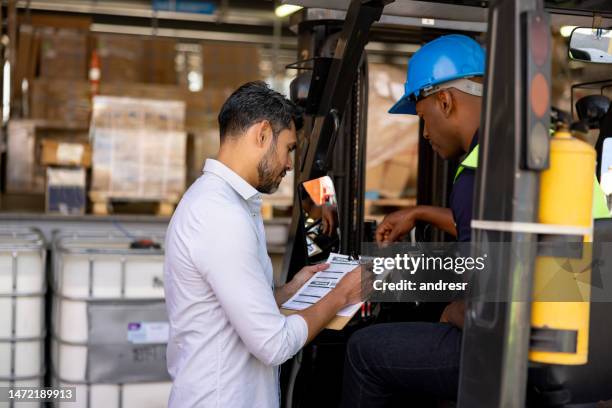 manager talking to a forklift driver at a distribution warehouse - unloading stockfoto's en -beelden