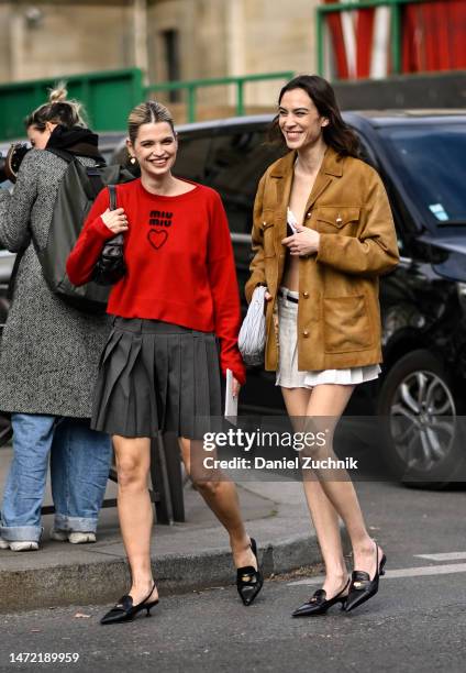 Pixie Geldoff is seen wearing a red Miu Miu sweater, gray Miu Miu skirt and black shoes with a black bag with Alexa Chung seen wearing a tan Miu Miu...