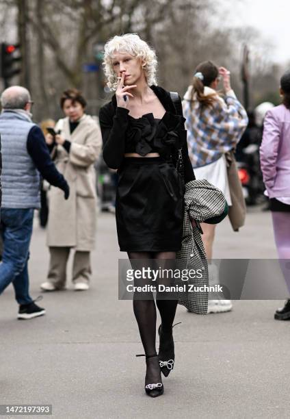 Model Maty Drazek is seen wearing a black ruffled top, black skirt, checkered coat and black and white shoes outside the Miu Miu show during Paris...