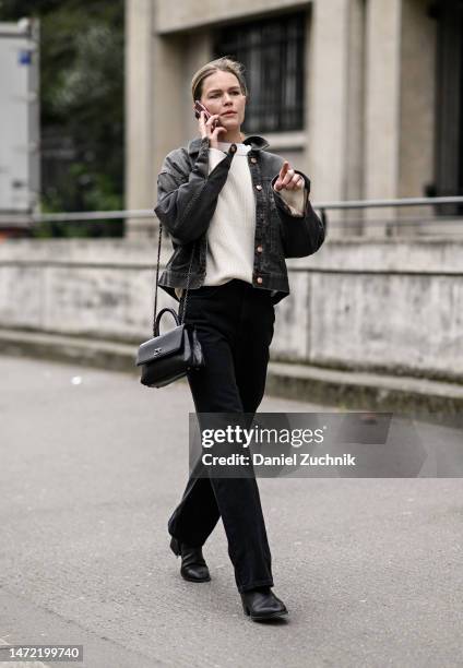 Model Anna Ewers is seen wearing a gray jean jacket, cream sweater, black pants and black Chanel bagoutside the Miu Miu show during Paris Fashion...