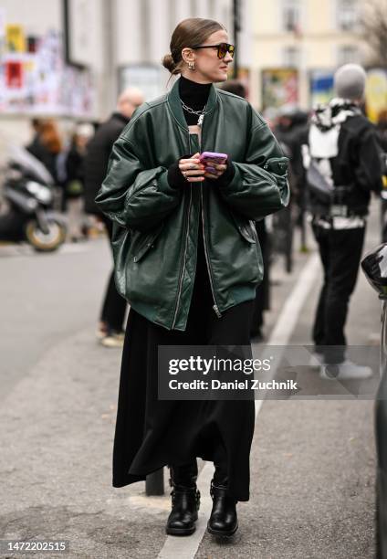 Guest is seen wearing a green bomber jacket, black dress and black boots outside the A.W.A.K.E. Mode show during Paris Fashion Week F/W 2023 on March...