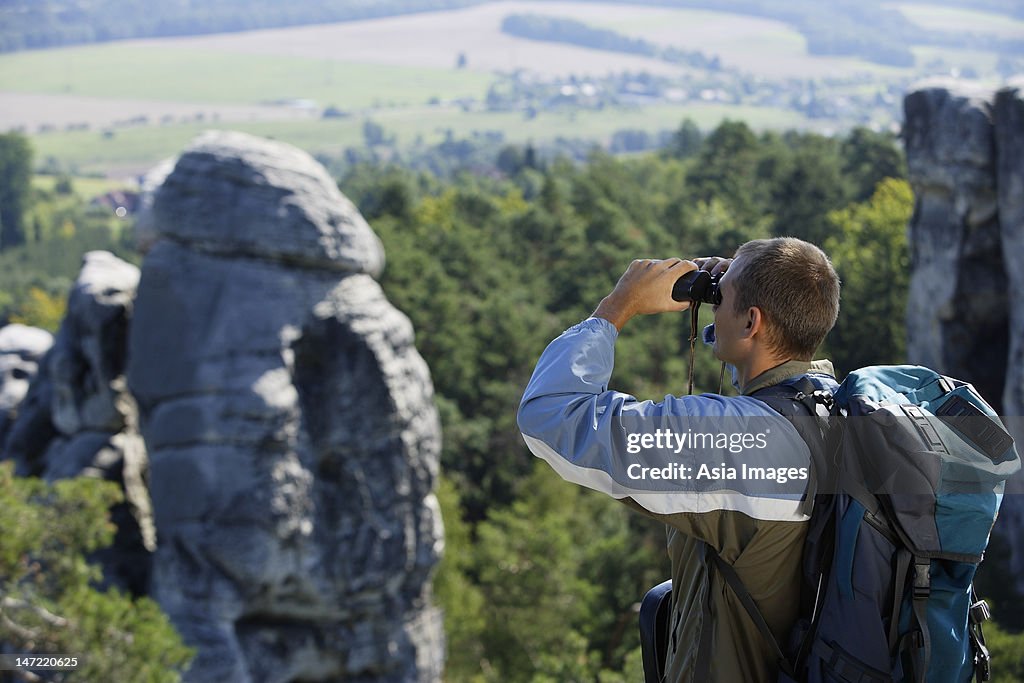 Young man viewing mountains with binoculars