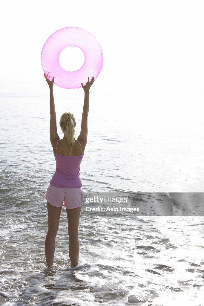 Woman at beach with pink tube