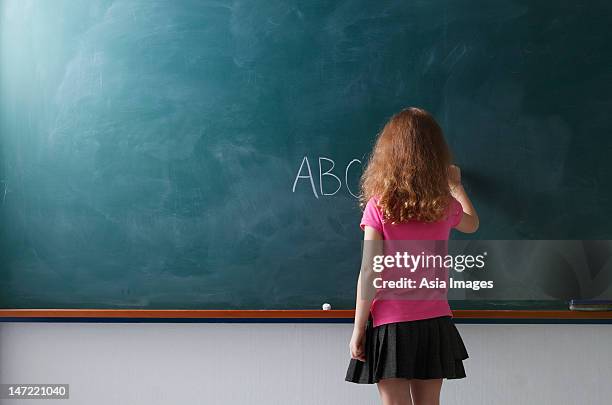 rear view of young girl writing on chalkboard - child writing on chalkboard stock pictures, royalty-free photos & images