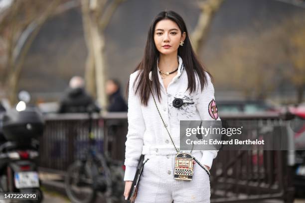 Guest wears a black pearls with gold logo necklace from Chanel, a white tweed with embroidered pink and black yoke buttoned tweed jacket from Chanel...