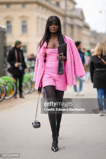 Guest wears a pink and white shoulder-off tweed short jumpsuit, a neon pink and white tweed jacket from Chanel, gold bracelets, gold rings, a black...