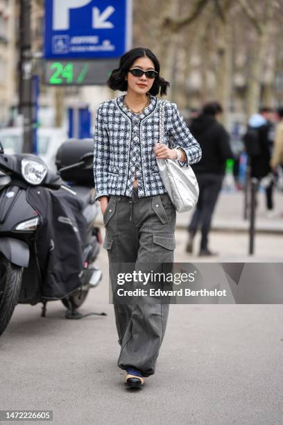 Guest wears black with white embroidered pearls sunglasses, a gold large chain pendants necklace from Chanel, a white and black with blue tweed...