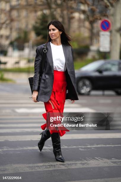 Guest wears a whit t-shirt, a black shiny leather blazer jacket, a black shiny leather shoulder bag, a neon red cut-out checkered pattern midi skirt,...