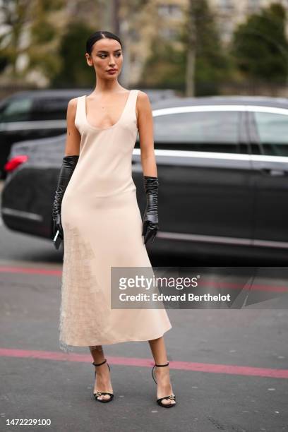 Guest wears a beige V-neck / tank-top / silk midi dress, black shiny leather high gloves, black shiny leather belted heels shoes , outside Awake,...