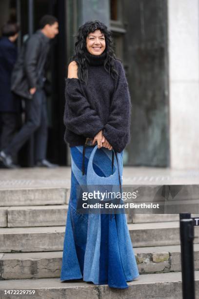 Guest wears a black turtleneck fluffy / cut-out shoulder details pullover, a dark and pale blue embroidered bicolored large fringed midi skirt, green...
