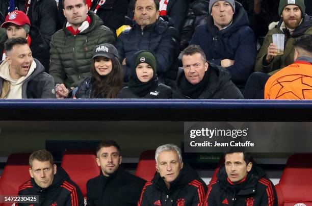 Lothar Matthaus and Anastasia Klimko - wearing a 'Paris' cap - attend above the bench of Bayern Munich the UEFA Champions League round of 16 leg two...