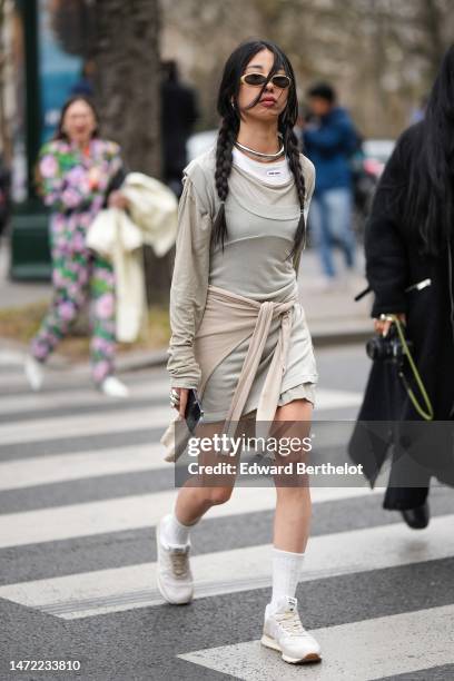 Guest wears beige sunglasses, silver earrings, a silver necklace, a white tank-top from Miu Miu, a pale brown long sleeves t-shirt, a pale khaki...