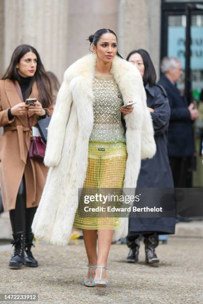 Guest wears a white fur long coat, a pale green with embroidered sequined and rhinestones long sleeves t-shirt from Miu Miu, a yellow tulle with...