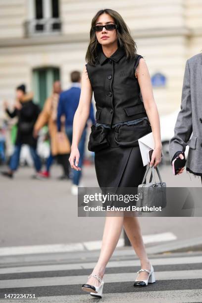 Guest wears black sunglasses, silver earrings, a black shirt neck / ripped sleeveless / buttoned shirt from Miu Miu, a black silk / satin wrap knees...