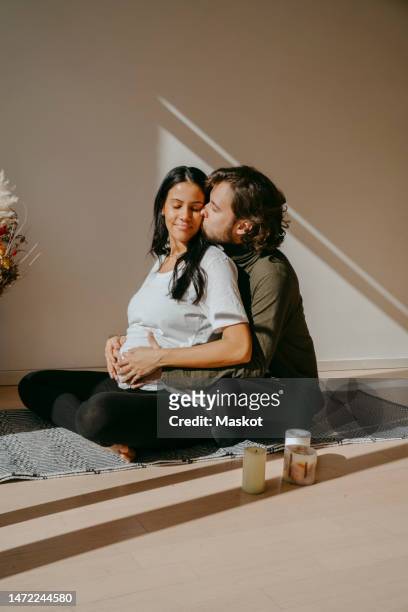 romantic expectant couple doing yoga with each other in exercise room - yoga rug photos et images de collection