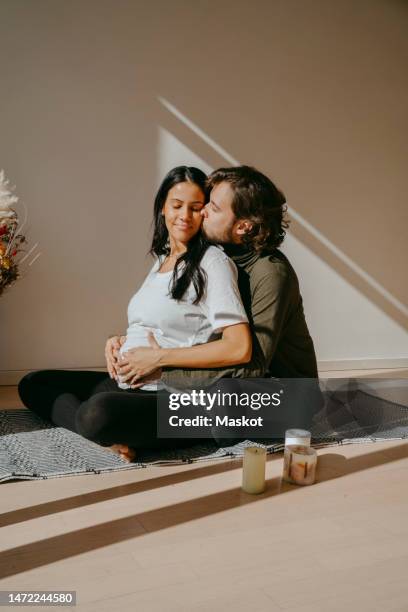 romantic expectant couple doing yoga with each other in exercise room - prenatal yoga stock pictures, royalty-free photos & images