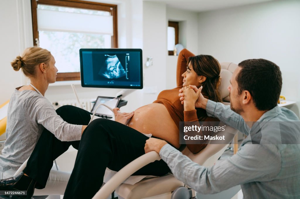 Doctor doing ultrasound of pregnant woman lying down at maternity clinic