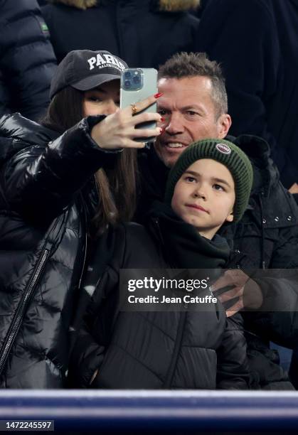 Lothar Matthaus and Anastasia Klimko - wearing a 'Paris' cap - attend the UEFA Champions League round of 16 leg two match between FC Bayern Munich...