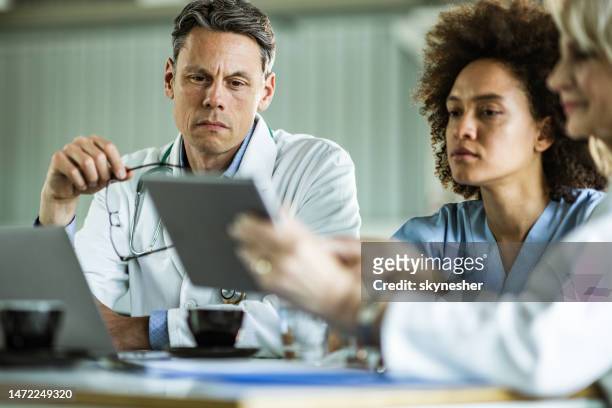 team of medical experts working on digital tablet at doctor's office. - doctor reading stock pictures, royalty-free photos & images