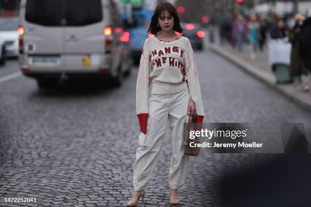 Emma seen wearing a white beige pullover with red details, beige wide pants, brown heels and a brown leather handbag, outside Stella McCartney during...