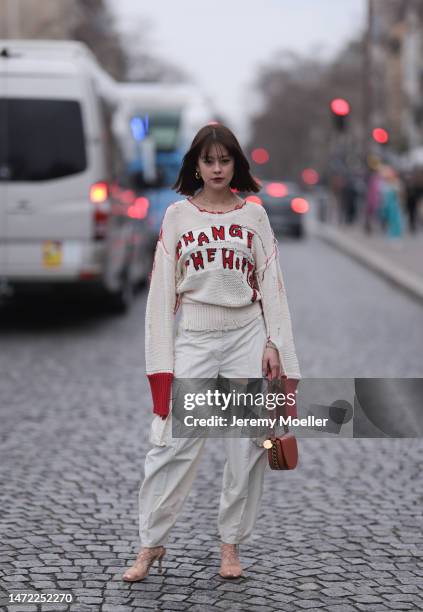 Emma seen wearing a white beige pullover with red details, beige wide pants, brown heels and a brown leather handbag, outside Stella McCartney during...