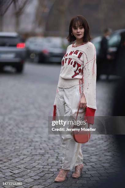 Emma seen wearing a white beige pullover with red details, beige wide pants, brown heels and a brown leather handbag, outside Stella McCartney during...