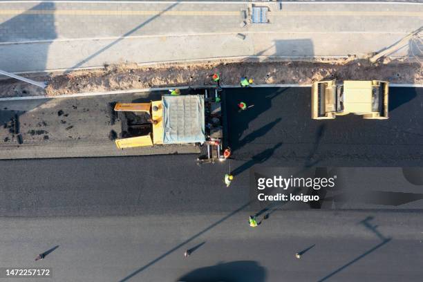 paving machinery and workers are laying asphalt road - asphalt paving stock pictures, royalty-free photos & images