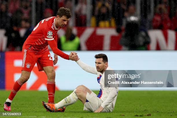 Thomas Mueller of FC Bayern Munich helps up Lionel Messi of Paris Saint-Germain during the UEFA Champions League round of 16 leg two match between FC...