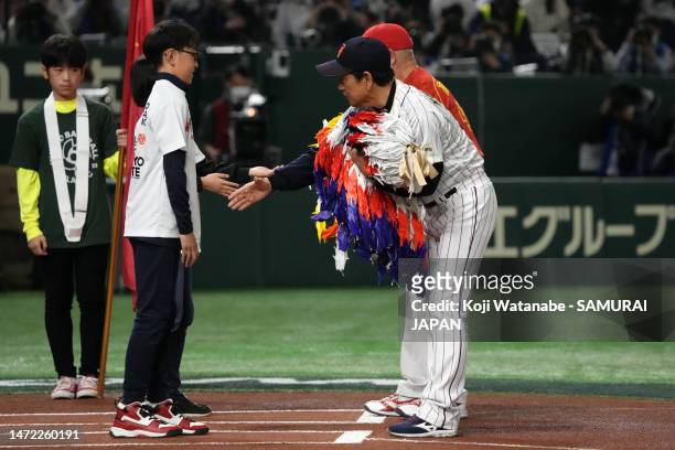 Manager Hideki Kuriyama of Japan and Manager Dean Trenor of China receive paper cranes prior to the World Baseball Classic Pool B game between China...