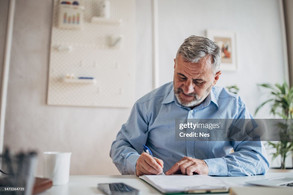 A man signs a paper document with a pen