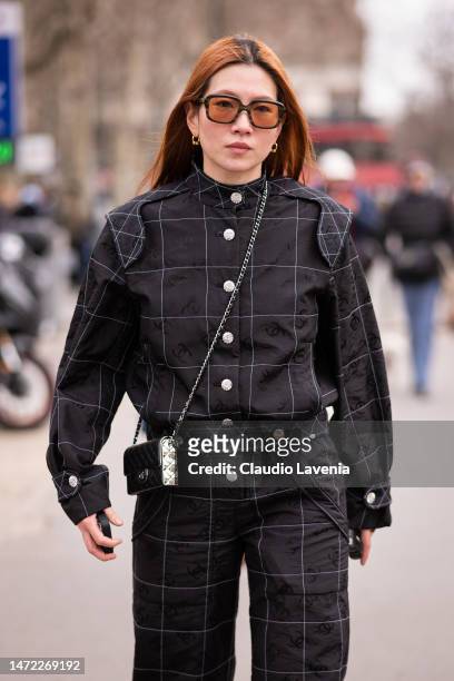 Guest wears a black Chanel jumpsuit, Chanel bag, outside Chanel, during Paris Fashion Week - Womenswear Fall Winter 2023 2024, on March 07, 2023 in...