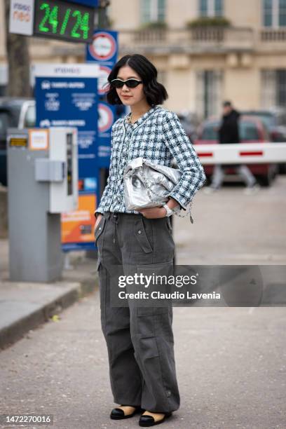 Guest wears a blue checked Chanel jacket, silver Chanel bag and grey cargo pants, outside Chanel, during Paris Fashion Week - Womenswear Fall Winter...