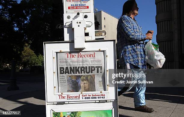 Pedestrian walks by a Stockton Record newspaper rack displaying the headline "Bankrupt!" on June 27, 2012 in Stockton, California. Members of the...