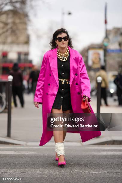 Clervie Rose wears black sunglasses, gold logo and fringed pendant earrings from Chanel, a gold large double chain necklace, a black tweed / gold and...