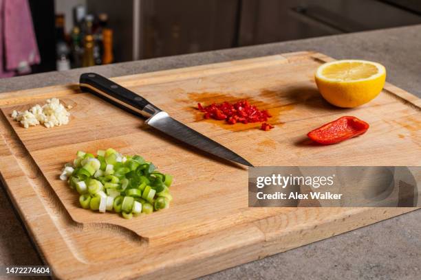 chopped vegetables and fruit on wooden chopping board with kitchen knife. - chopped stock pictures, royalty-free photos & images