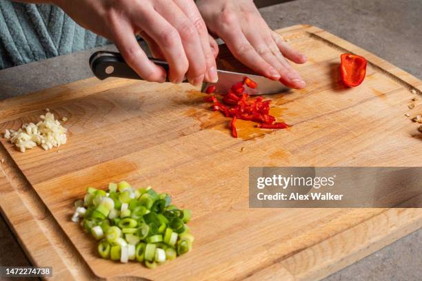 a person finely chopping red chilli pepper on wooden chopping board. - five a day stock pictures, royalty-free photos & images