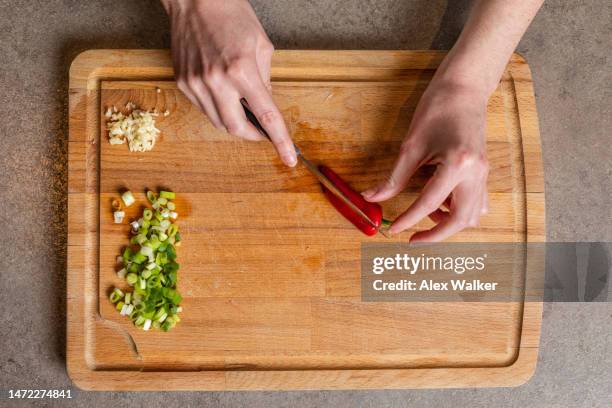 a person chopping red chilli pepper on wooden chopping board. - five a day stock pictures, royalty-free photos & images