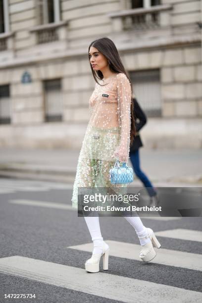 Guest wears silver earrings, a beige ribbed tank-top from Miu Miu, a beige tulle with embroidered sequined long sleeves t-shirt from Miu Miu, a pale...
